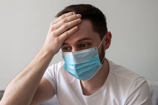 Scared Man in medical mask looks in camera. Scared man in fear of coronavirus stands in protective medical mask against viruses and infections isolated studio. Coronavirus 2019-ncov covid-19 concept. - Fotografie, Obrázek