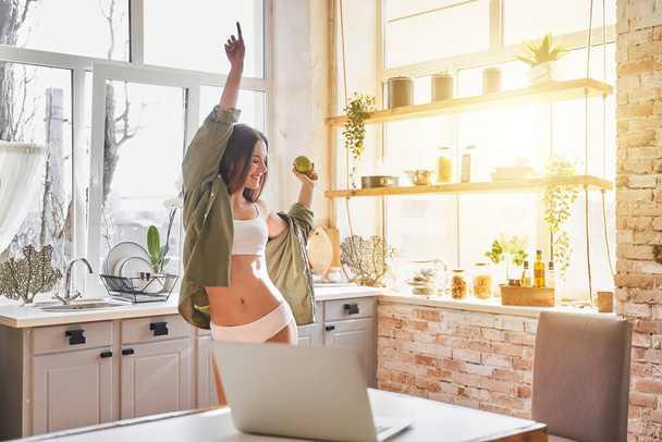 Positive delighted young female dancing in her kitchen - Foto, Imagem