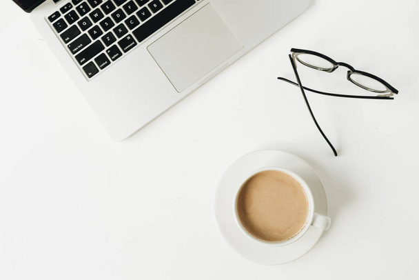 Moderner Schreibtisch im Home Office mit Laptop, Tasse Kaffee, Brille auf weißem Hintergrund. Flache Verlegung, Arbeit von oben, Geschäftskonzept. - Foto, Bild