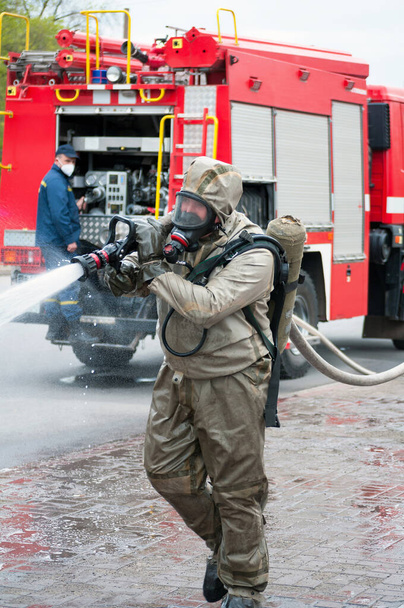 Rettungsteam desinfiziert Straße mit spezieller dekontaminierender Flüssigkeitslösung während Covid-19-Katastrophe aus Feuerwehrauto - Foto, Bild