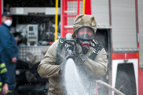 equipe de resgate desinfetando rua com solução líquida descontaminante especial enquanto desastre covid-19 do motor de bombeiros
 - Foto, Imagem