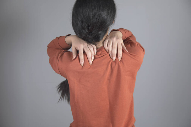 woman hand in ache shoulder on grey background - Valokuva, kuva