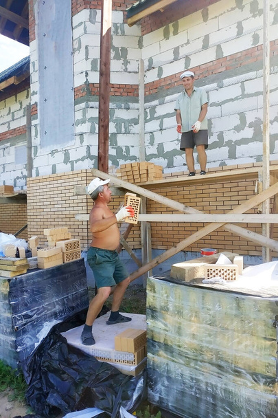Хозяин бросает кирпич в своего работника за то, что тот заложил стену. 2019 год
 - Фото, изображение