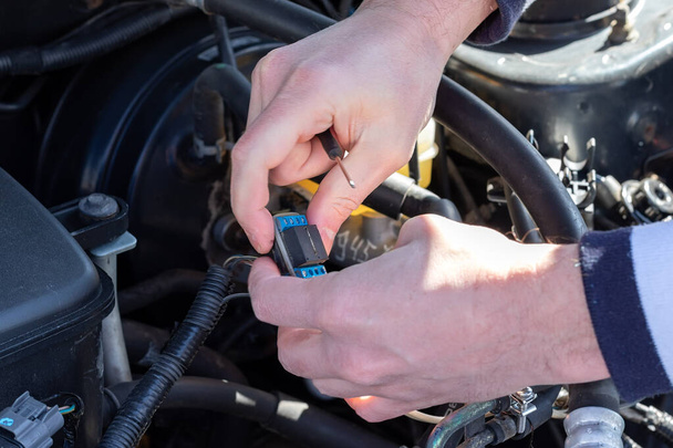 Male hands with a small screwdriver connect an electronic component under the open hood of a flat-four (boxer) car - Photo, Image