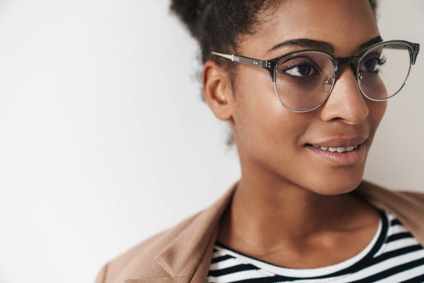 Portrait closeup of african american cute woman in eyeglasses smiling and looking forward isolated over white background - 写真・画像