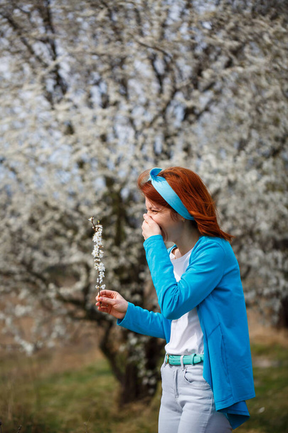 Nuori nainen seisoo puutarhassa, jossa kirsikat ja aprikoosit kukkivat. Hän on onnellinen hengitys ilmaa, kevät kukkia taustalla
 - Valokuva, kuva