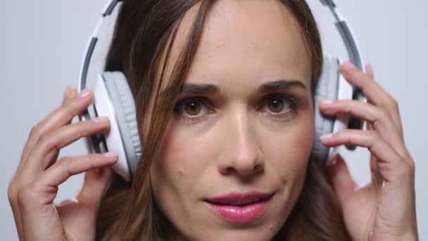 Business woman putting on headphones. Woman listening music in earphones - Materiaali, video