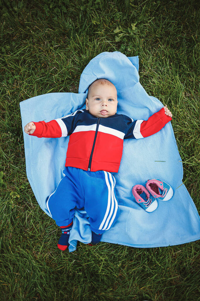 Adorable baby girl lying on the grass on a summer day. Family activities with kids. Summer picnic with a chil - Фото, зображення