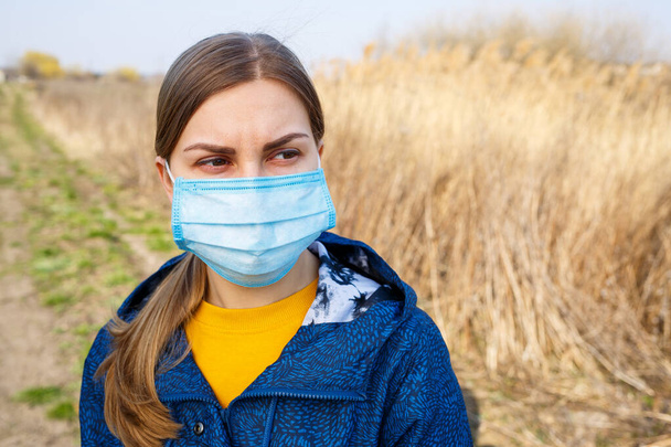 Close up Portrait Woman Outdoor in Surgical mask with rubber ear straps. Typical 3-ply surgical mask to cover the mouth and nose. Procedure mask from bacteria. Protection concept. - Photo, Image