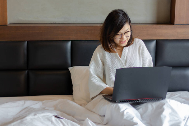 nuori liiketoiminnan nainen, joka käyttää kannettavaa tietokonetta sängyssä työskennellessään kotoa covid-19-kriisin aikana
. - Valokuva, kuva