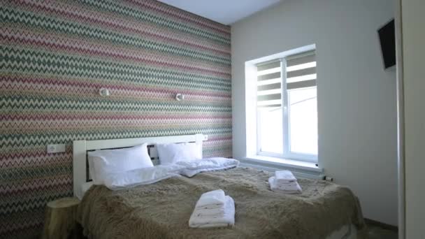 Innenraum eines geräumigen Hotelschlafzimmers mit frischer Bettwäsche auf einem großen Doppelbett. Gemütliches zeitgenössisches Zimmer in einem modernen Haus. - Filmmaterial, Video