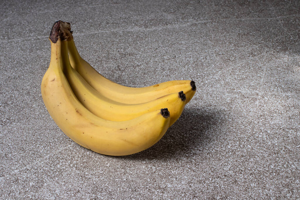 Bananen auf grauem Steingrund. Drei reife gelbe Bananen. - Foto, Bild
