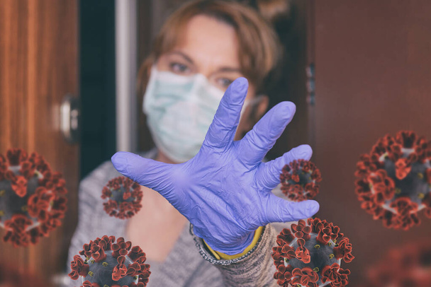 コロナウイルスの流行のために彼女の家のドアを開ける保護面を身に着けている女性covid-19 。隔離と隔離の概念 - 写真・画像