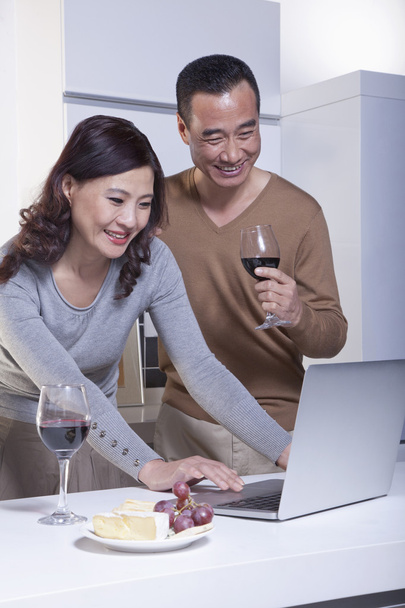 Mature Couple Looking at Laptop in the Kitchen - Photo, Image