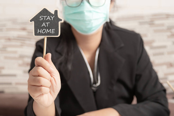 Evden ve sosyal uzaklık kavramından çalışmak için tahtanın üzerinde "Evde Kal" kelimesini gösteren bir kadın. Enfeksiyonla savaşmak ve Coronavirüs veya COVID-19 salgınından korumak için karantina. - Fotoğraf, Görsel
