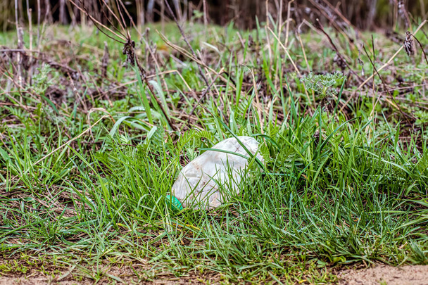 szemét üres műanyag palack fekszik a zöld fű az erdőben. koncepció ökológia és újrahasznosítás - Fotó, kép