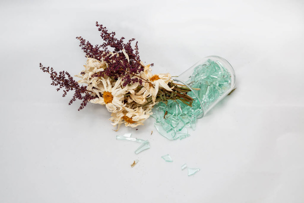 ramo marchito, flores secas viejas en un jarrón de vidrio roto. concepto de otoño, sueños rotos, fondo blanco
 - Foto, Imagen