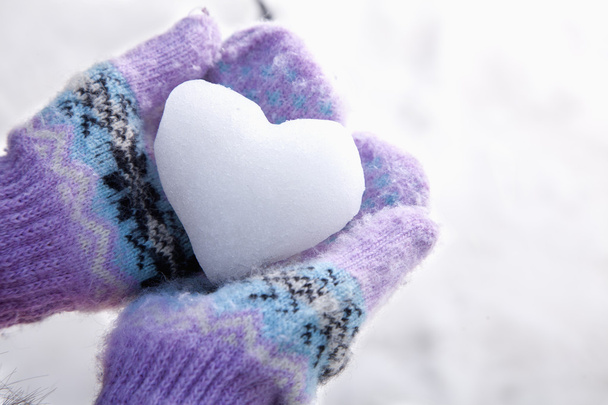 Corazón de nieve en las manos con manoplas
 - Foto, Imagen