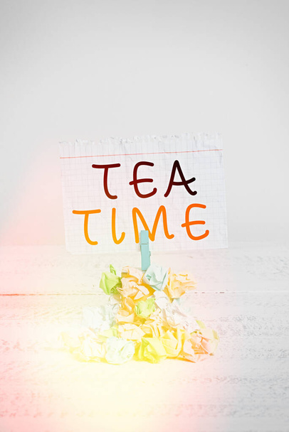Handschriftliches Textschreiben Tea Time. Konzept, das die Zeit am Nachmittag meint, wenn einige Zeigende eine kleine Mahlzeit essen Erinnerungsstapel farbig zerknülltes Papier Wäscheklammer Erinnerung weißer Holzraum. - Foto, Bild