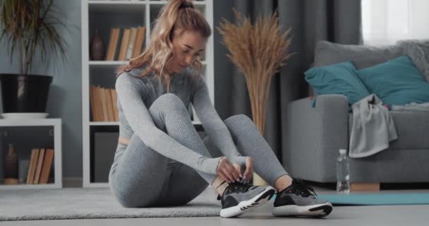 Fitness woman tying laces on sneakers at home - Filmmaterial, Video