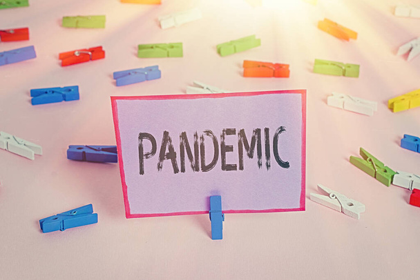 Writing note showing Pandemic. Business photo showcasing occurring over a wide area affecting high proportion of population Colored clothespin papers empty reminder pink floor office pin. - Photo, Image