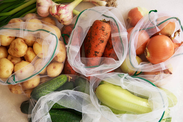 zero waste shopping concept. fresh vegetables in eco cotton bags on table in the kitchen. lettuce, corn, potatoes, apricots, bananas, rucola, mushrooms from market. ban plastic. - Foto, immagini