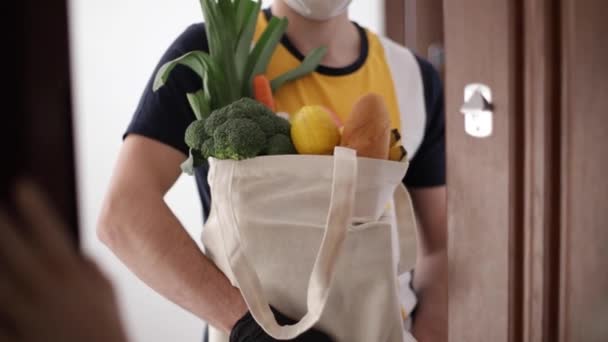 Delivery man in mask and gloves bring fresh food to customers home. Stay home. Online shopping concept - Video
