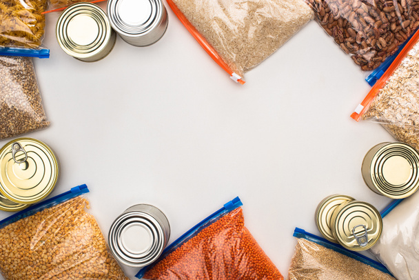 top view of cans and groats in zipper bags on white background, food donation concept - Zdjęcie, obraz