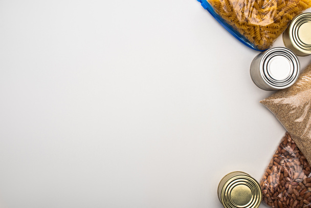 vista superior de latas e grumos em sacos de zíper no fundo branco, conceito de doação de alimentos
 - Foto, Imagem