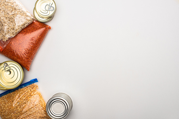 πάνω άποψη των κονσερβοκούτια και groats σε σακούλες φερμουάρ σε λευκό φόντο, ιδέα δωρεά τροφίμων - Φωτογραφία, εικόνα