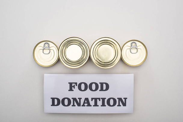 acostado plano con latas sobre fondo blanco con tarjeta de donación de alimentos
 - Foto, Imagen