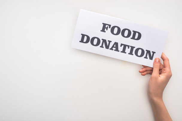 vista cortada da mulher cartão de retenção com letras de doação de alimentos no fundo branco
 - Foto, Imagem