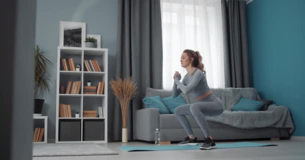 Sporty woman doing squats during workout at home - Felvétel, videó