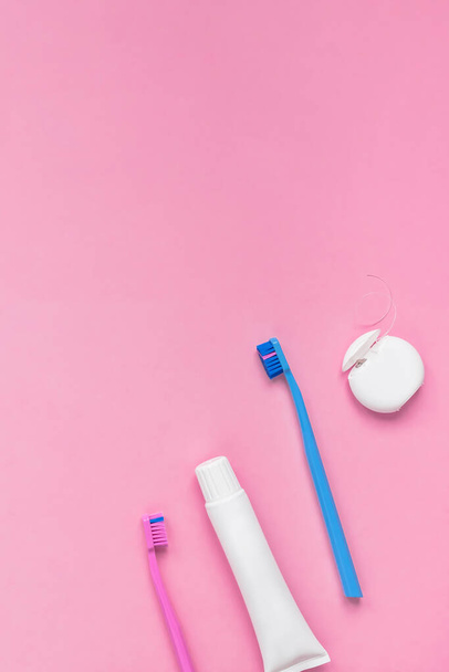 Zuby hygieny a ústní zubní péče produkty na barevném růžovém a modrém pozadí s kopírovacím prostorem. Prázdná tuba zubní pasty a kartáčků. Byt ležel, horní pohled kompozice, maketa. Ranní koncept - Fotografie, Obrázek