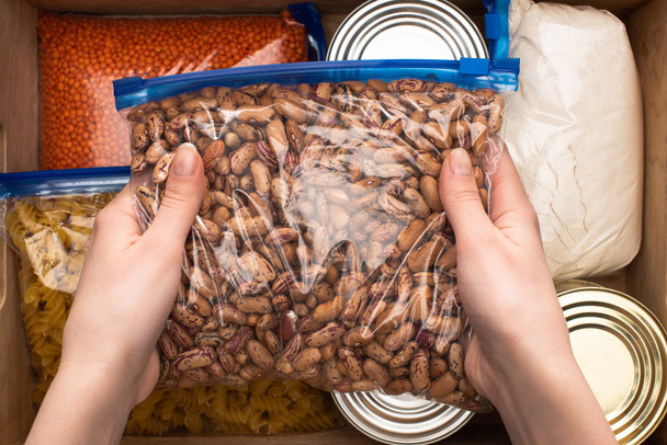 cropped view of woman holding  beans in zipper bag, food donation concept - Foto, afbeelding