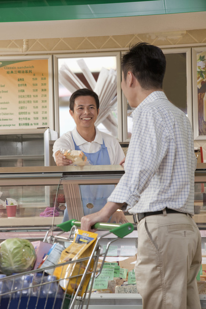 Verkäuferin hilft Mann am Delikatessenschalter - Foto, Bild