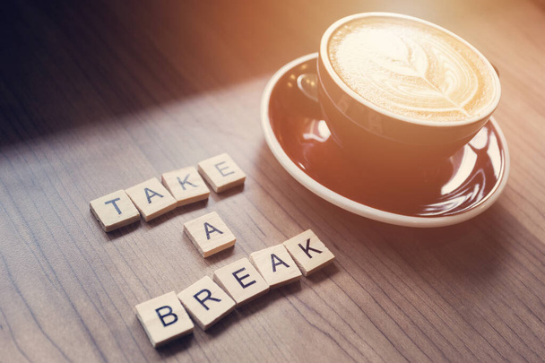 Cup of coffee on workplace desk, take a break word. - 写真・画像