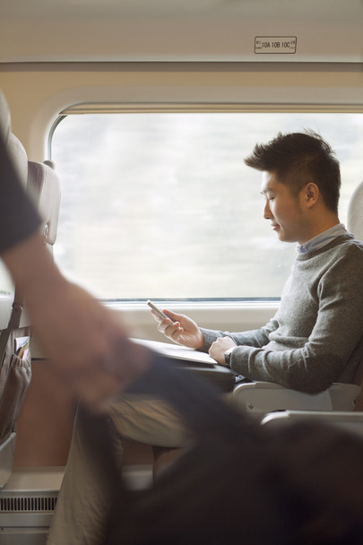 Man sitting on a train using his phone - Foto, afbeelding