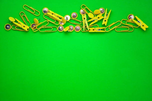 Materiales de oficina en forma de botones de colores y clips de papel, clavijas de ropa sobre fondo amarillo y verde, espacio de copia, borde y marco, de vuelta al concepto escolar de la cancillería de oficina
 - Foto, Imagen