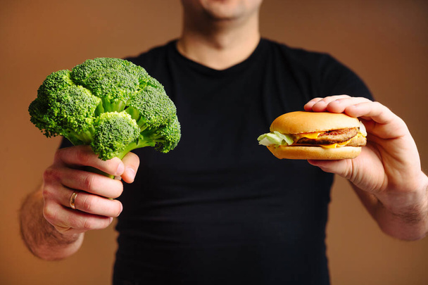 The choice between healthy food broccoli and unhealthy junk food hamburger. - Valokuva, kuva