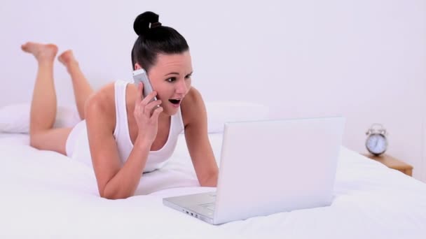Beautiful woman phoning while using her notebook - Кадри, відео
