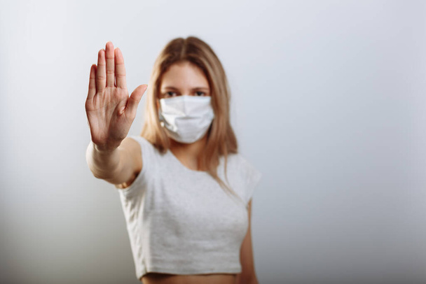 Kobieta w masce pokazuje znak stopu ręką, aby zapobiec rozprzestrzenianiu się wirusów. Skupienie selektywne. - Zdjęcie, obraz