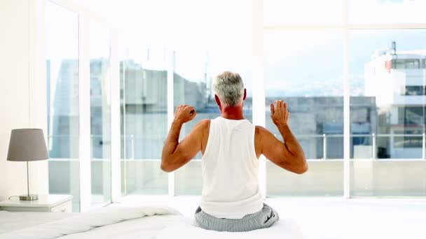 Mature man yawning and stretching sitting on bed - Video, Çekim