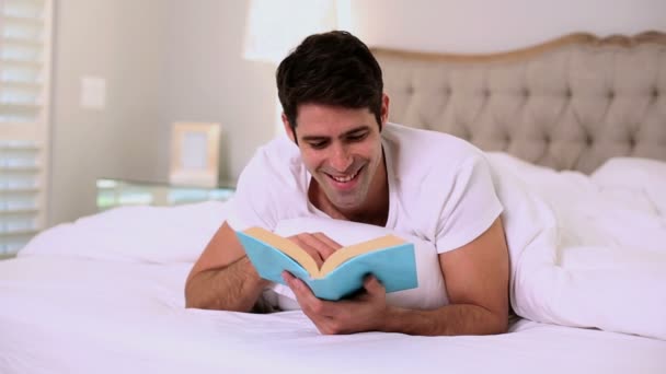 Happy handsome man reading in bed - Footage, Video