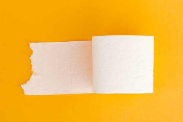 Rollo de papel higiénico sobre fondo amarillo
 - Foto, Imagen