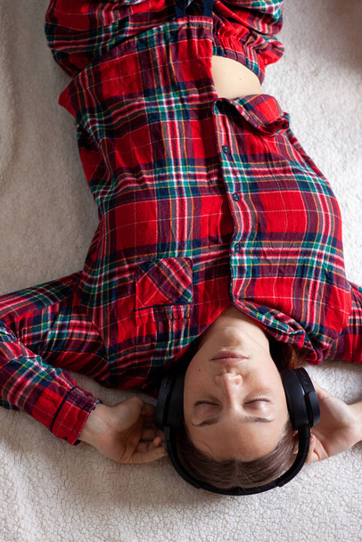 Giovane donna in cuffia rilassante sul divano di casa
 - Foto, immagini