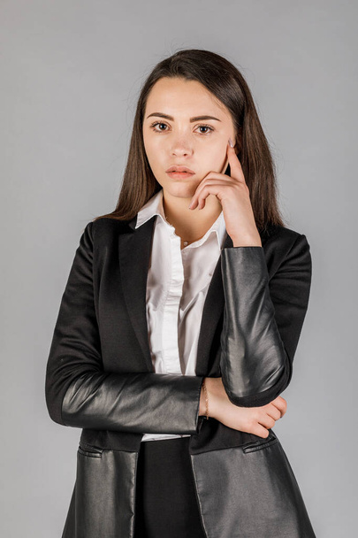 Young business woman in dark suite on grey background. Office concept - Φωτογραφία, εικόνα