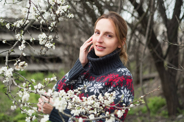 Girl with a lovely smile and white flowers. Portrait of a european girl in spring. White flowers on a wild tree - Foto, imagen