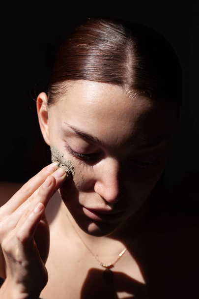 Portrait of beautiful woman applying some cream to her face for skin care - Foto, Imagem
