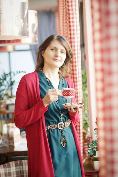 młoda blondynka z filiżanką herbaty portret przez okno kawiarni zbliżenie zdjęcie - Zdjęcie, obraz